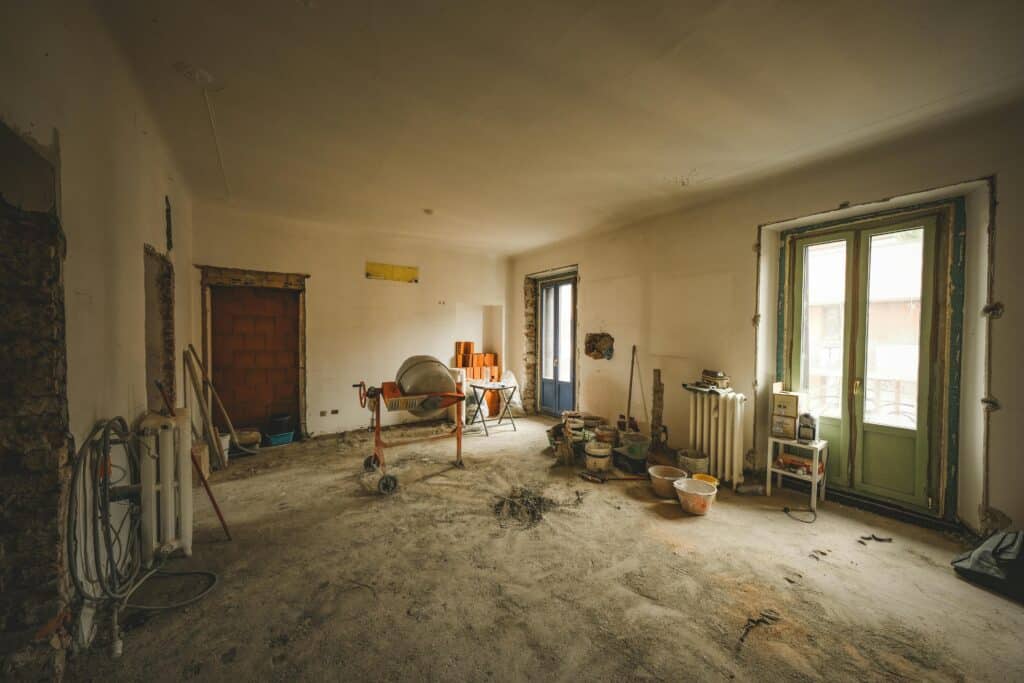 Vue d'ensemble d'une pièce ensoleillée en cours de rénovation, avec des matériaux et des outils de construction présents, idéale pour des idées d'aménagement intérieur.