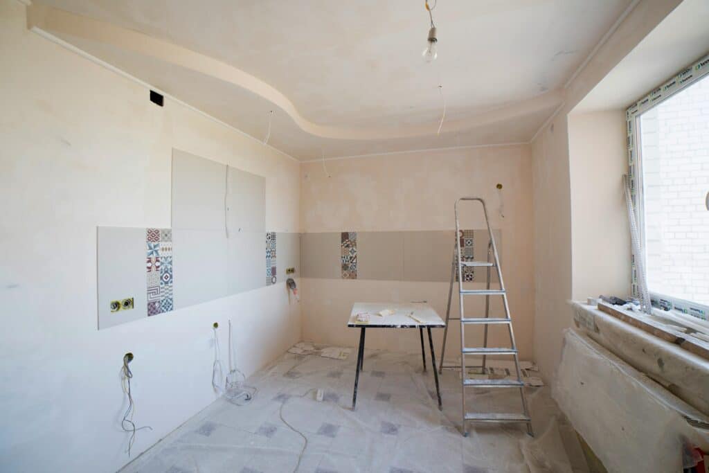 Cuisine spacieuse en cours de rénovation, avec échelle et outils, dévoilant un tout nouveau design.