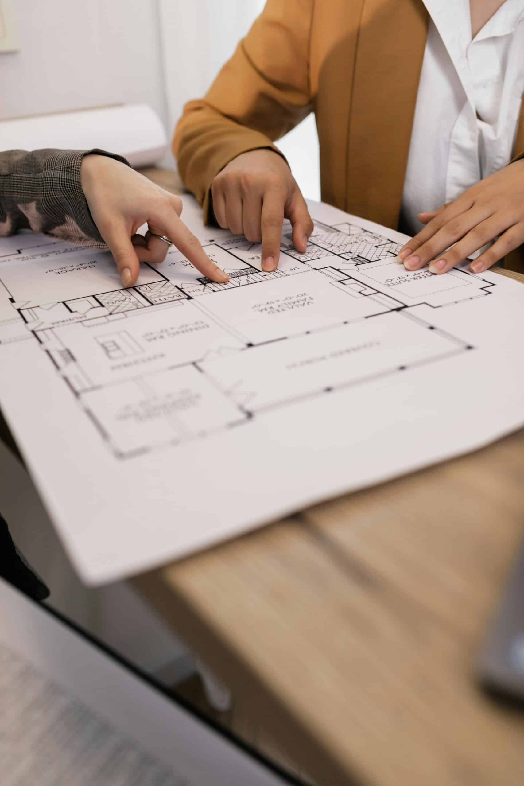 Ma Méthode Cocon Design 3 Deux personnes discutent des détails d'un plan d'architecture dans un bureau